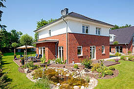 Haus Meinke Massivhaus mit roten Backsteinen Außenansicht Terasse und Garten mit Teich