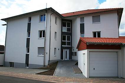 Vorderseite des Mehrfamilienhauses mit separaten Garagen am Eingang