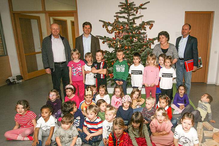 Kinder und Erwachsene vor einem Weihnachtsbaum