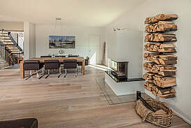 Haus Schönborn Innenansicht Wohnzimmer mit Essbereich, Kamin und Feuerholz